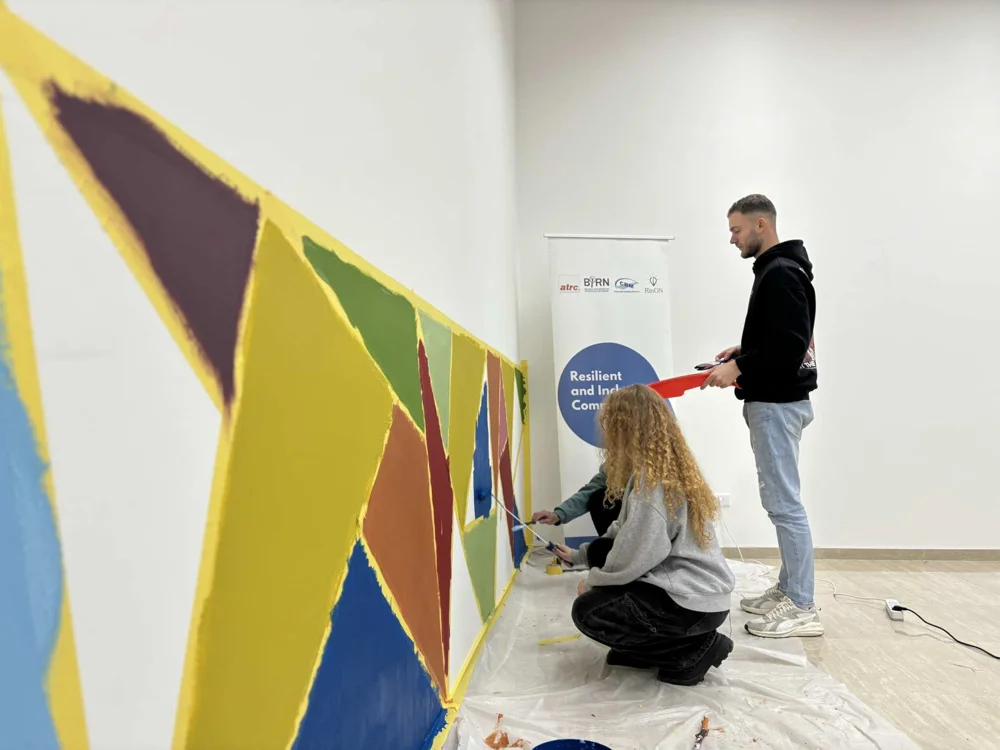 Volunteers painting a mural inside the Cultural Centre in Mirash